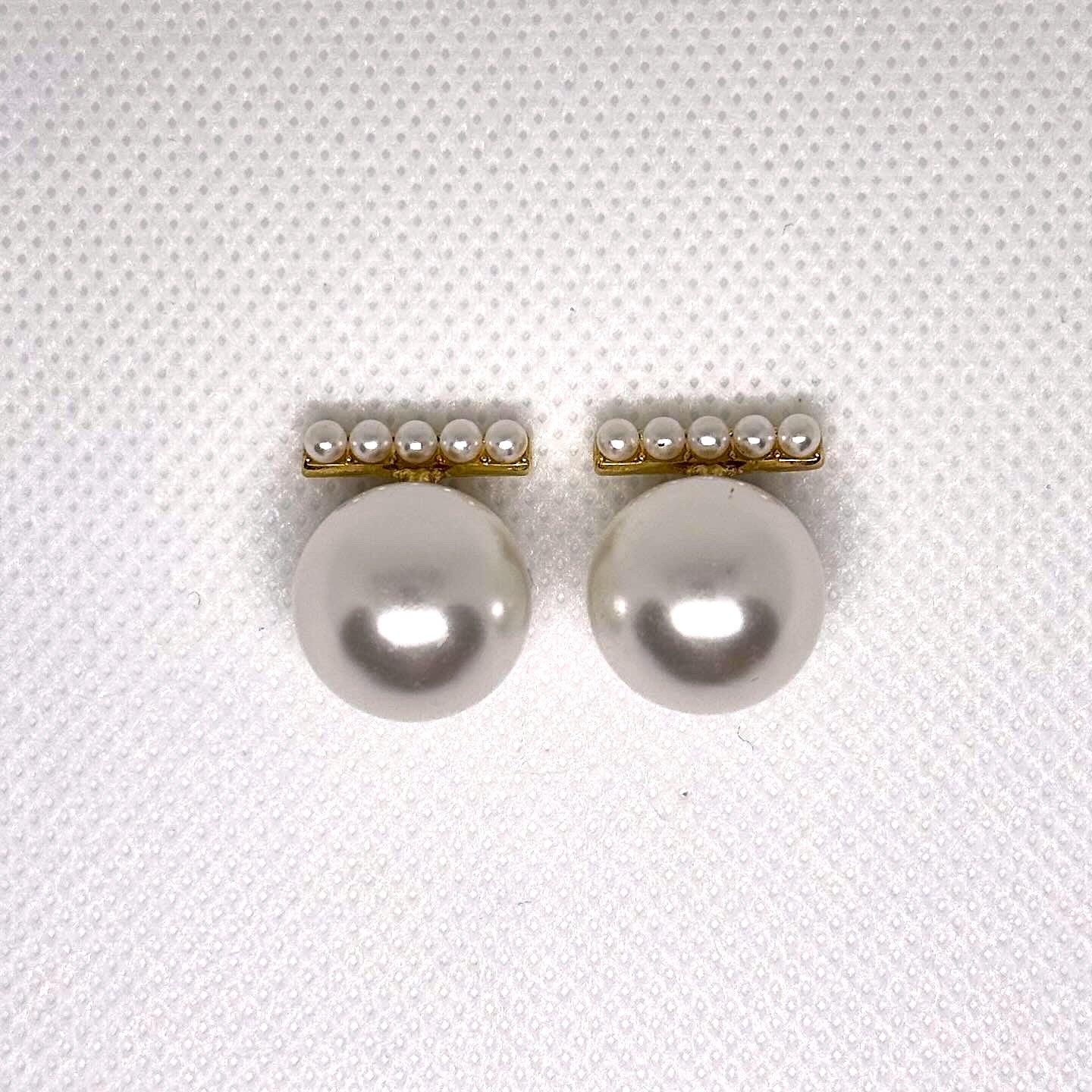 Pair of pearl earrings on a textured white background