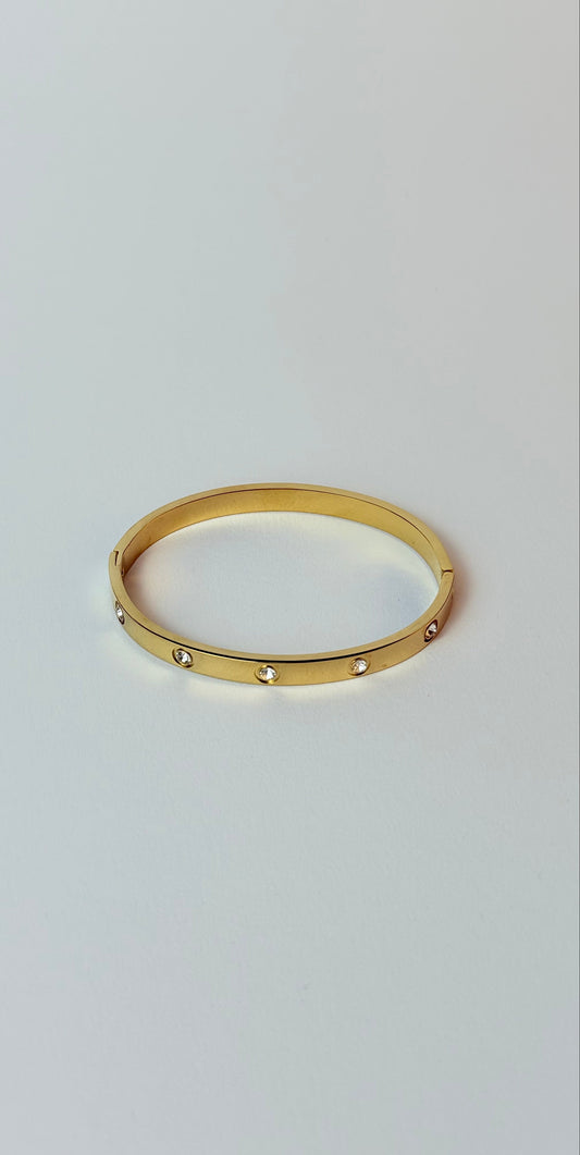 Gold ring with small stones on a light gray background