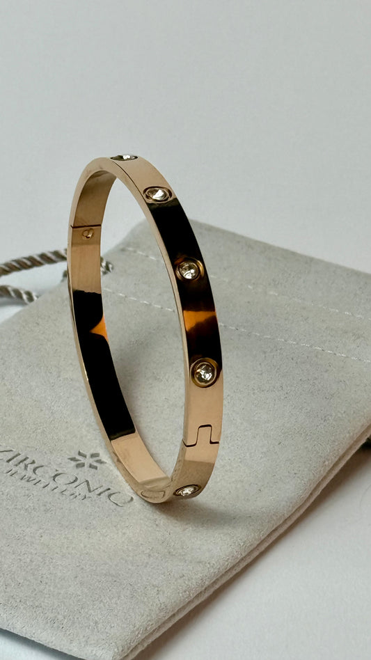 Gold bracelet with gemstones on a light gray surface