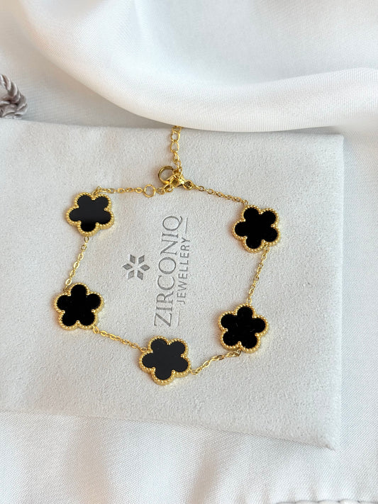 Gold bracelet with black flower-shaped charms on a Zirconiq Jewellery branded card.