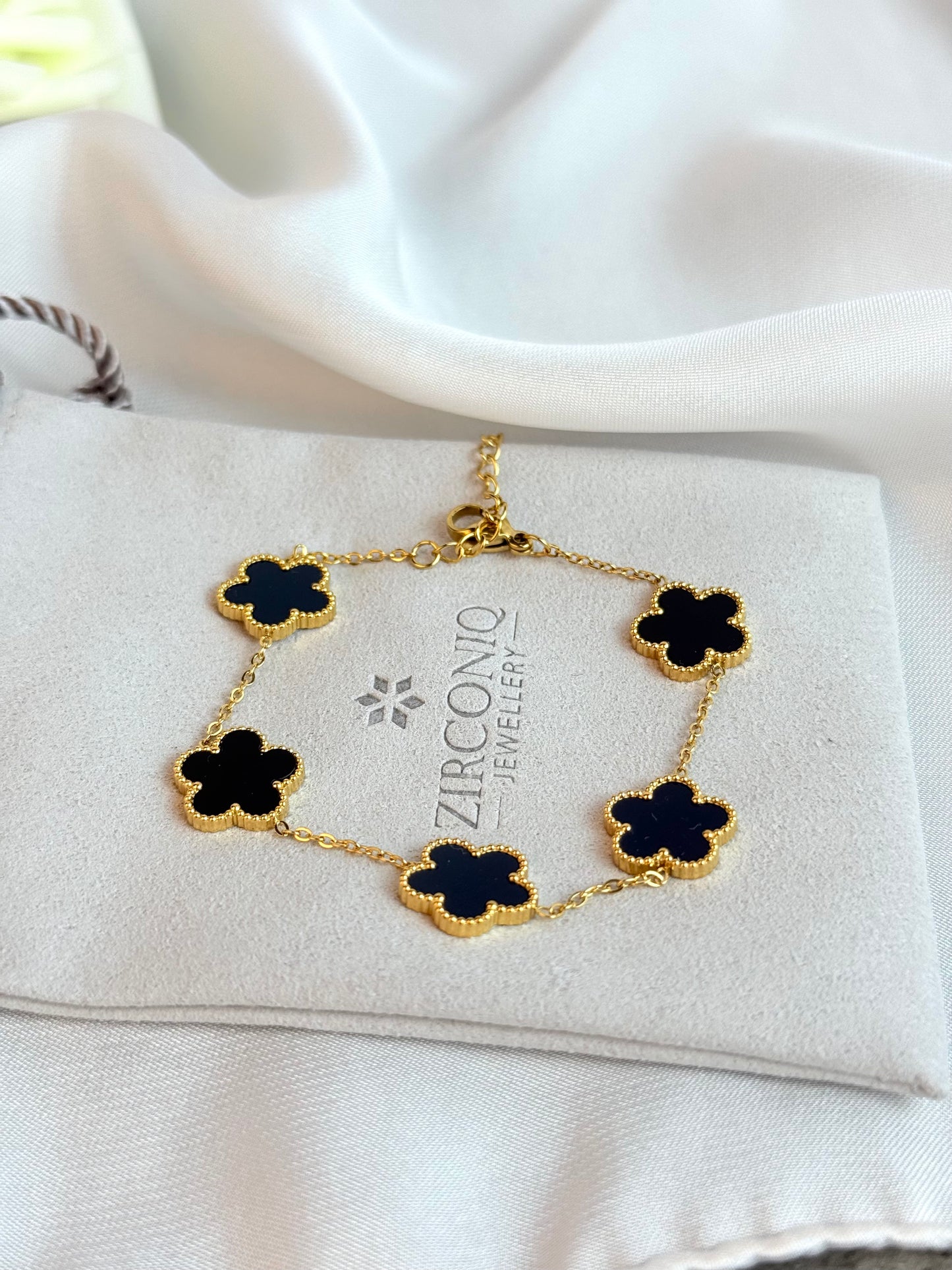 Gold bracelet with black flowers on a Zirconio Jewellers card