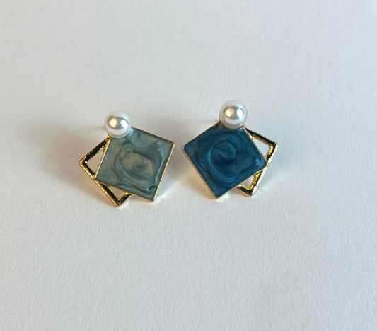 Pair of square earrings with blue centers and gold borders on a white background