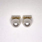 Pair of pearl earrings on a textured white background