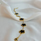 Gold necklace with black clover-shaped pendants on a white fabric background