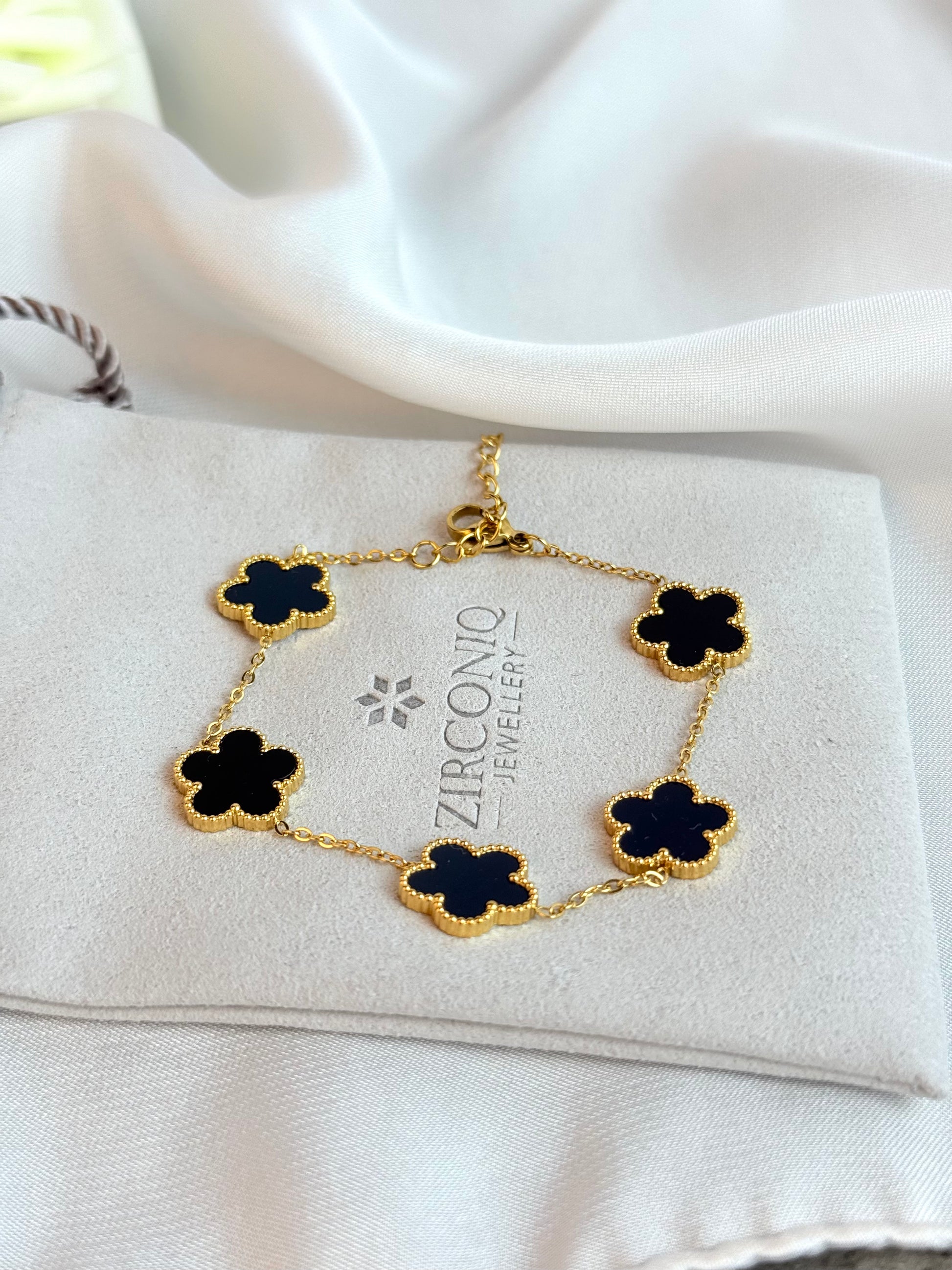 Gold bracelet with black flowers on a Zirconio Jewellers card