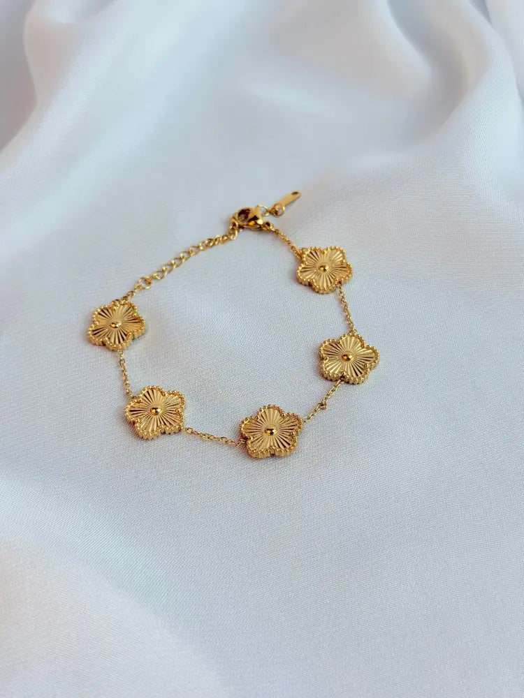 Gold bracelet with floral designs on a white fabric background
