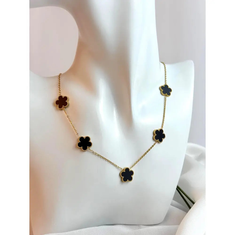 Necklace with black clover-shaped pendants on a mannequin bust.