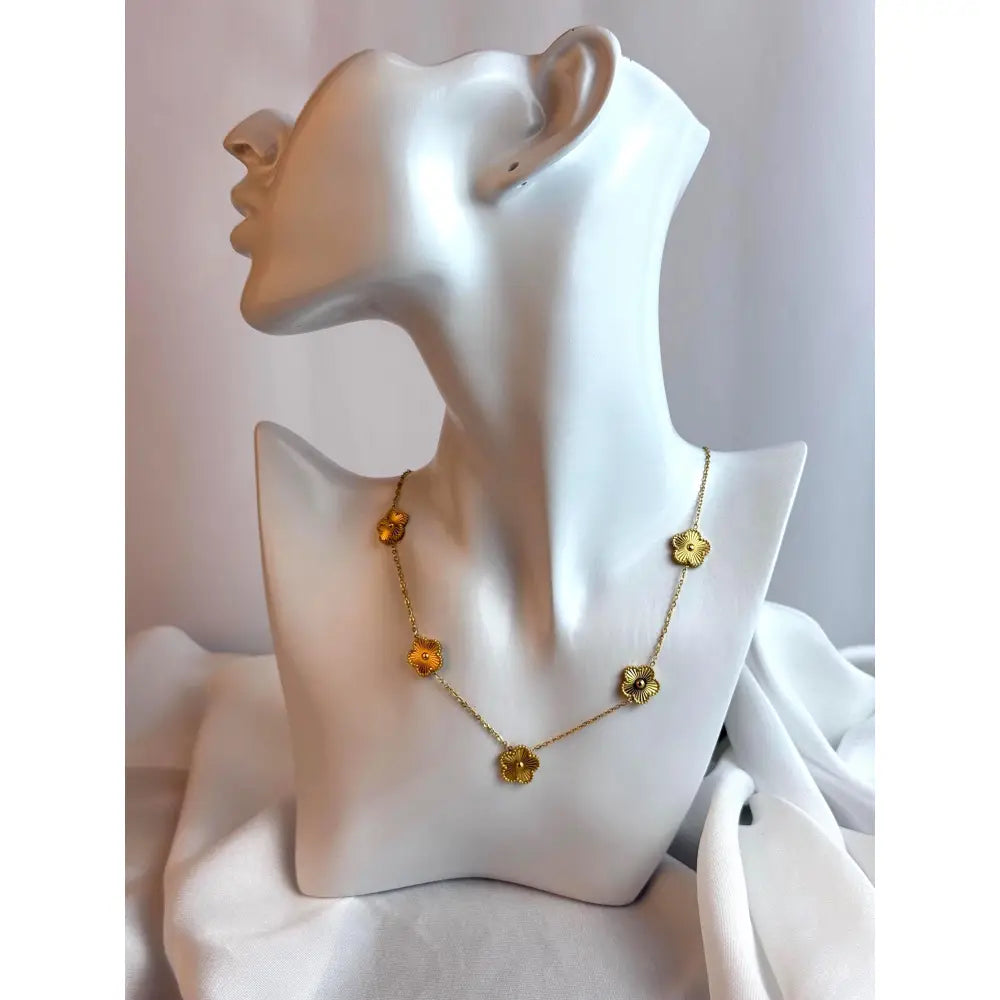 Gold necklace with floral designs on a mannequin bust against a white background
