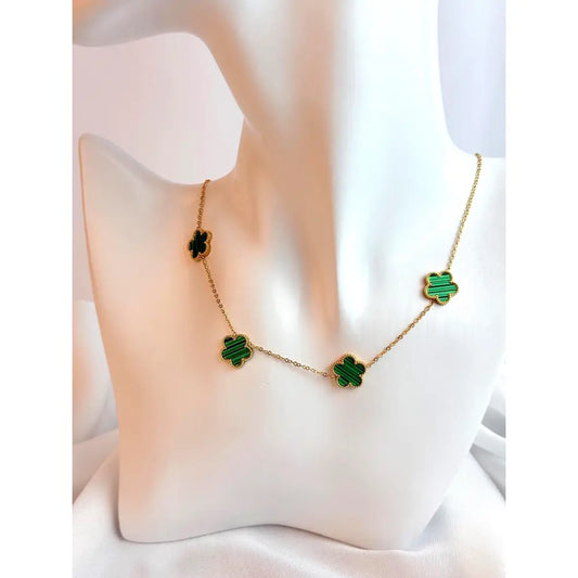 Gold necklace with green clover-shaped pendants on a white cushion
