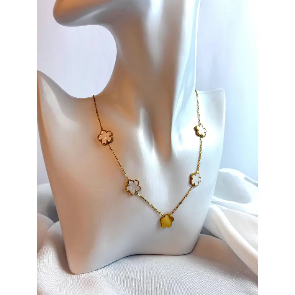 Gold necklace with floral pendants on a mannequin bust against a white background