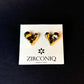 Heart-shaped gold earrings on a Zirconiq branded card against a black background
