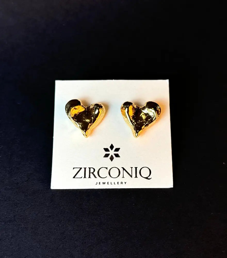 Heart-shaped gold earrings on a Zirconiq branded card against a black background