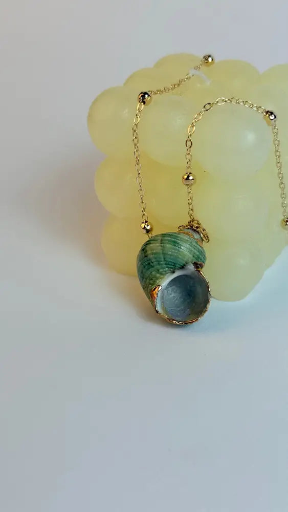 Necklace with a green shell pendant on a light background