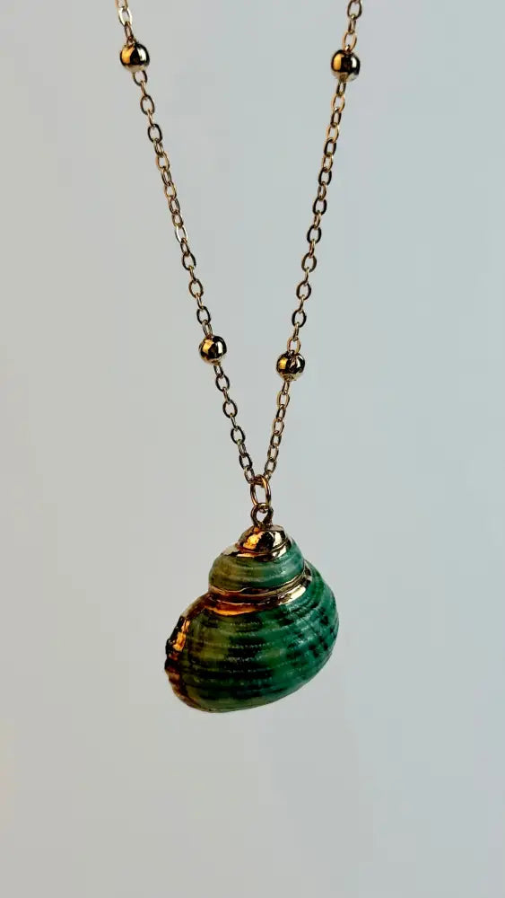 Necklace with a green shell pendant on a light gray background