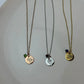 Three necklaces with circular pendants on a white plate