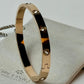 Gold bracelet with gemstones on a light gray surface